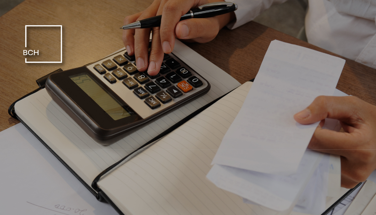 Mani di un consulente che utilizza una calcolatrice su documenti contabili per il calcolo del budget di cassa aziendale.